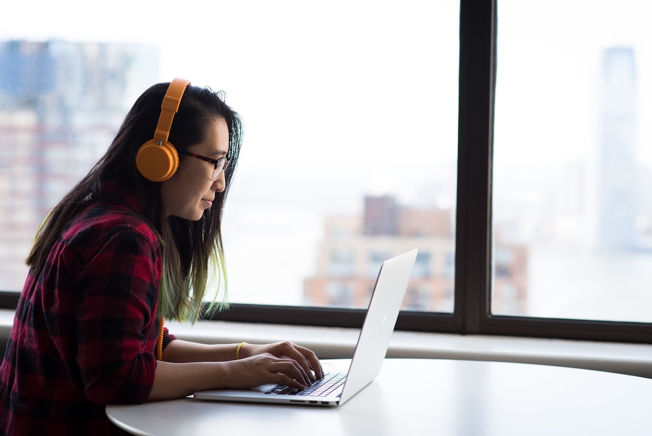 cloud solutions enable remote workers - woman works on laptop with yellow headphones on
